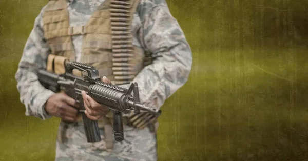 Soldado segurando uma arma contra fundo verde — Fotografia de Stock