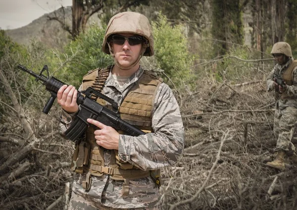 Soldier man holding a weapon against field background — Stock Photo, Image