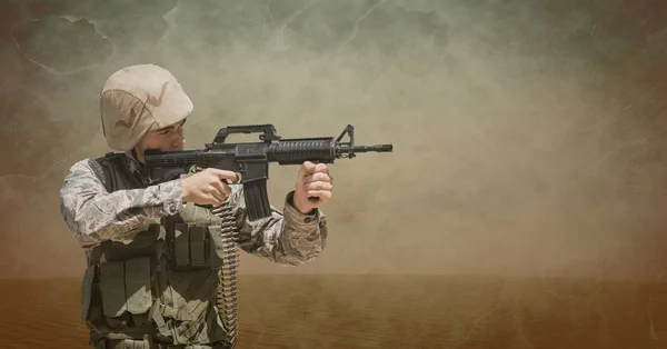 Soldier man holding a weapon against brown background — Stock Photo, Image