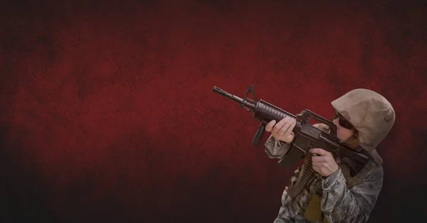 Soldat mannen håller ett vapen mot röd bakgrund — Stockfoto