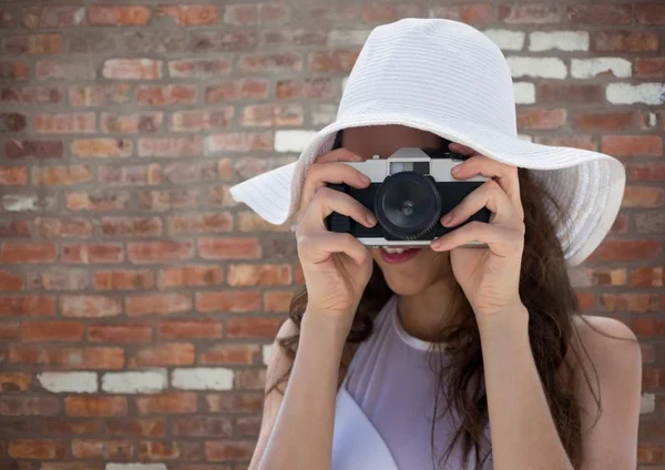 Duizendjarige vrouw in zomer hoed met camera tegen rode bakstenen muur — Stockfoto