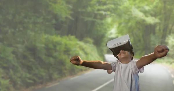 Хлопчик у гарнітурі VR піднімає руки на фоні дороги — стокове фото