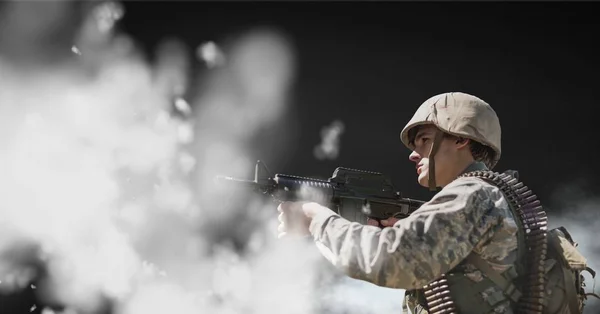 Soldado segurando uma arma contra fundo preto com nuvens — Fotografia de Stock