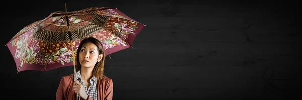 Millennial donna con ombrello fantasia contro pannello in legno scuro — Foto Stock