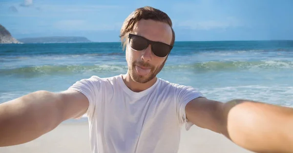 Millennial hombre tomando selfie y sacando la lengua contra la playa —  Fotos de Stock