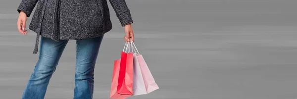 Shopper dolnej części ciała z torby przed rozmyte tło szare — Zdjęcie stockowe