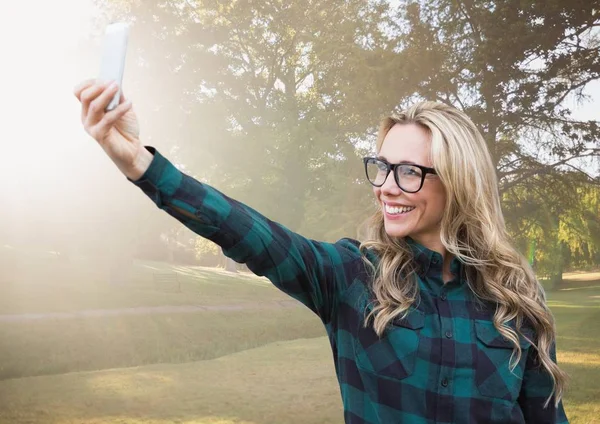 Mujer milenaria tomando selfie en parque borroso con bengala — Foto de Stock