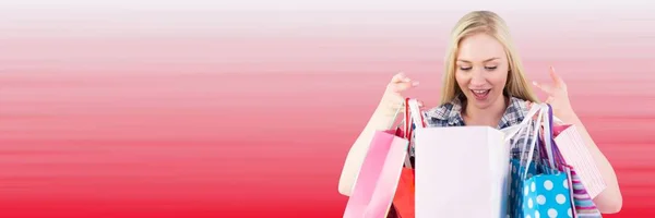 Shopper undersöker väskor mot suddiga röd bakgrund — Stockfoto