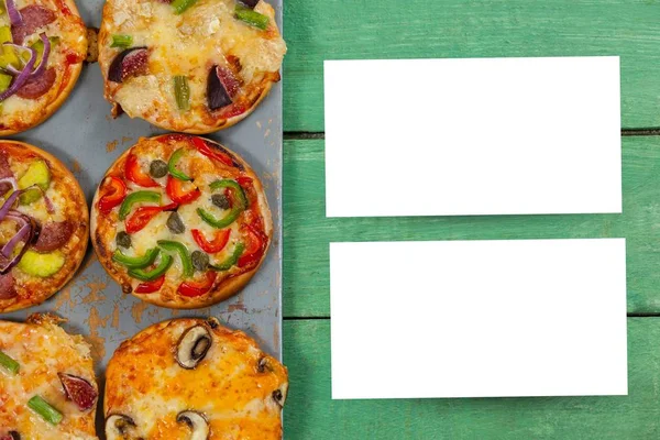 Twee vellen blanco papier op tafel naast pizza 's — Stockfoto