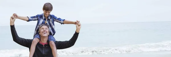 Zoon op vaders schouders op strand — Stockfoto