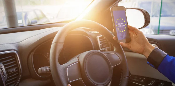 Hombre sosteniendo teléfono inteligente en su coche — Foto de Stock