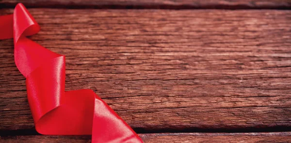 Krouživým pohybem červenou stuhou na dřevěný stůl — Stock fotografie