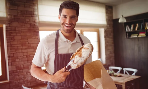 Bäcker packt Laib Brot ein — Stockfoto