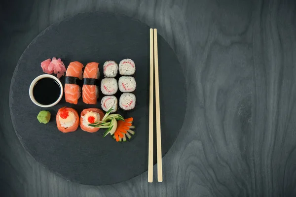 Japanisches Essen auf schwarzem Teller mit Essstäbchen — Stockfoto