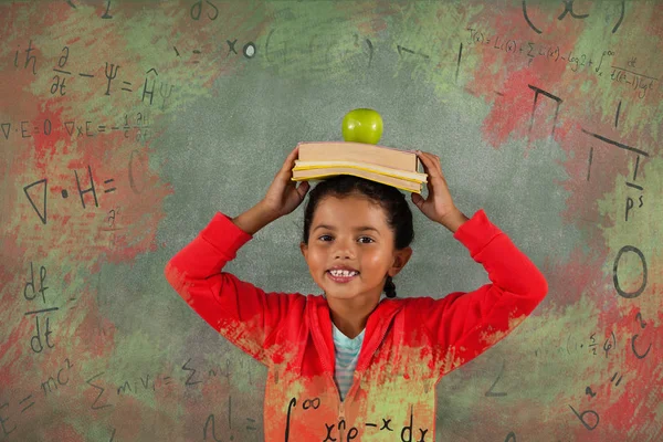 Chica equilibrio libros y manzana en la cabeza —  Fotos de Stock