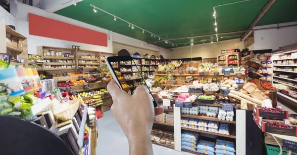 Mano usando el teléfono móvil en la tienda de comestibles — Foto de Stock