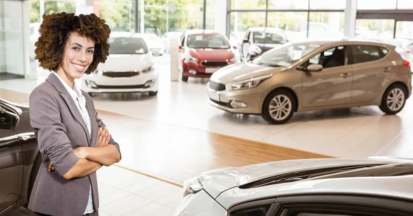 Selbstbewusste Verkäuferin steht im Verkaufsraum neben Autos — Stockfoto