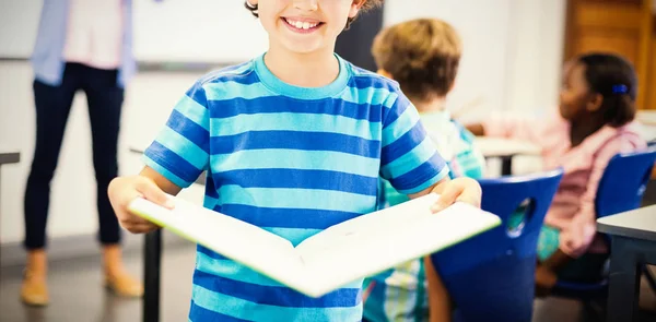 Uczniak stojąc z książki w klasie — Zdjęcie stockowe