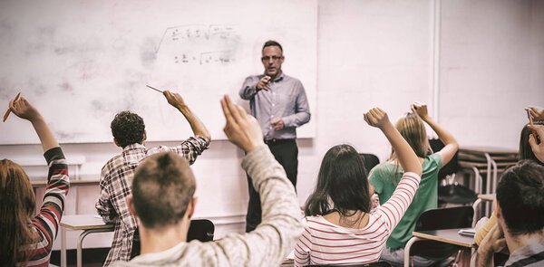 Students raising hands in classroom