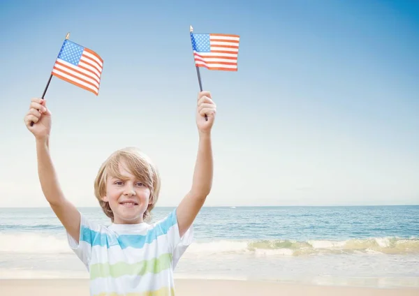 Niño feliz sosteniendo banderas de EE.UU. en la playa — Foto de Stock