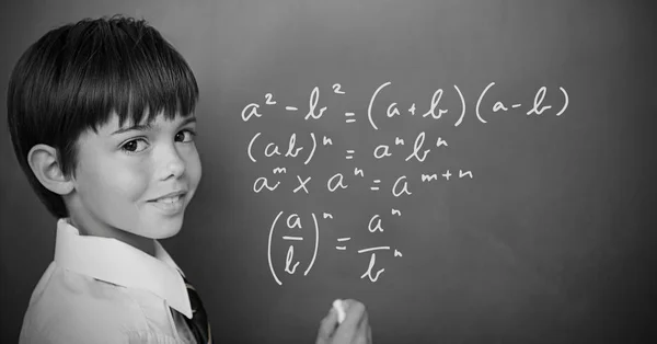 Junge schreibt mathematische Gleichungen auf Tafel — Stockfoto