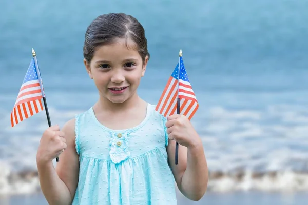 Chica sosteniendo banderas de EE.UU. en la playa — Foto de Stock