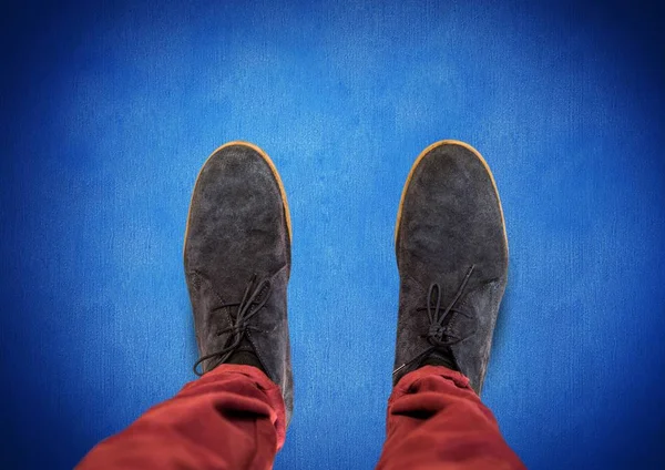Sapatos cinza em pés com fundo azul — Fotografia de Stock