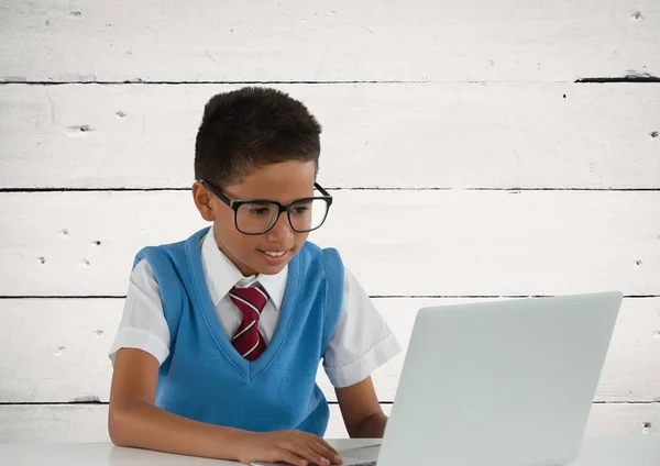 Schoolboy no laptop com fundo de madeira — Fotografia de Stock