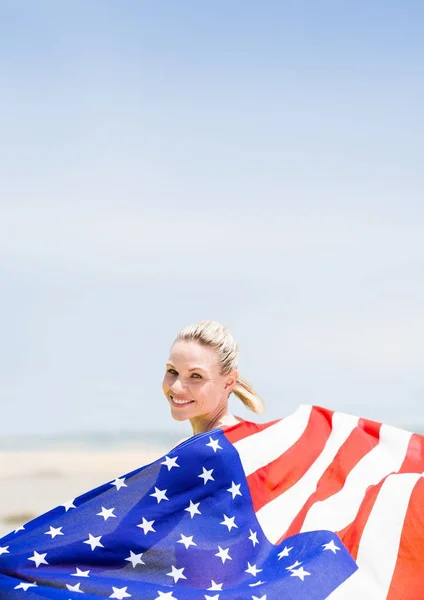 Mujer feliz sosteniendo una bandera de EE.UU. en la playa — Foto de Stock