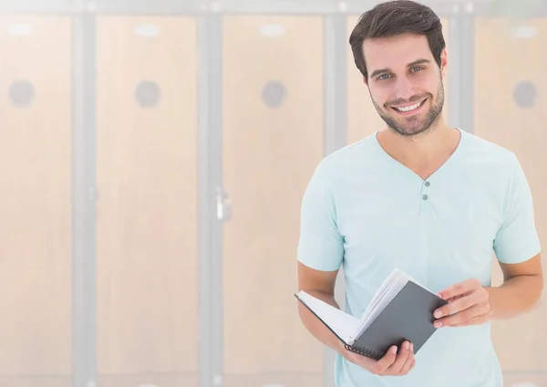 Студент мужчина держит книгу перед шкафчиками — стоковое фото