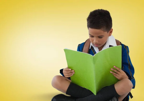 Školák čtení na žlutém podkladu — Stock fotografie