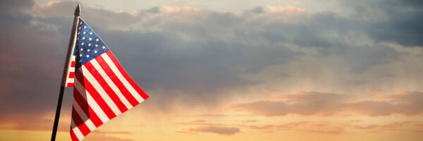 Американский флаг против живописного вида облачного неба
