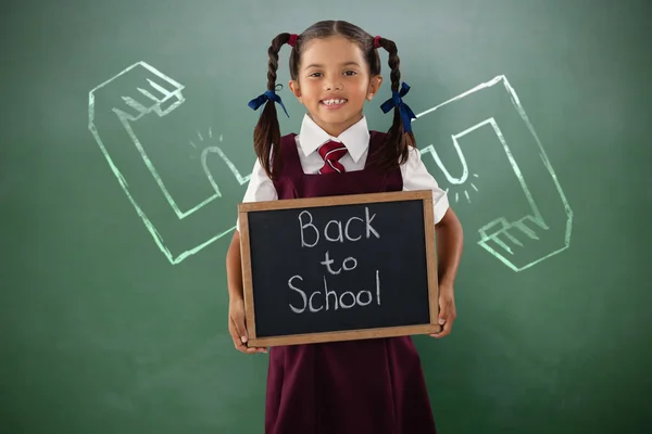 Sonriente colegiala sosteniendo pizarra — Foto de Stock