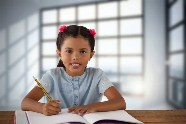 Chica escribiendo en libro en el escritorio — Foto de Stock