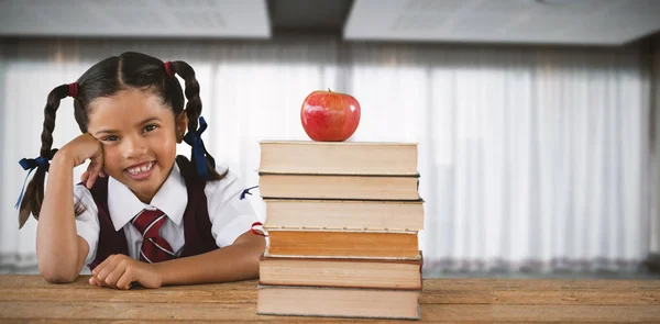 Uczennica, pochylony przez książek i apple na biurko — Zdjęcie stockowe