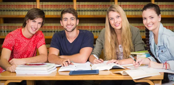 Students studying against bookshelf — Stock Photo, Image