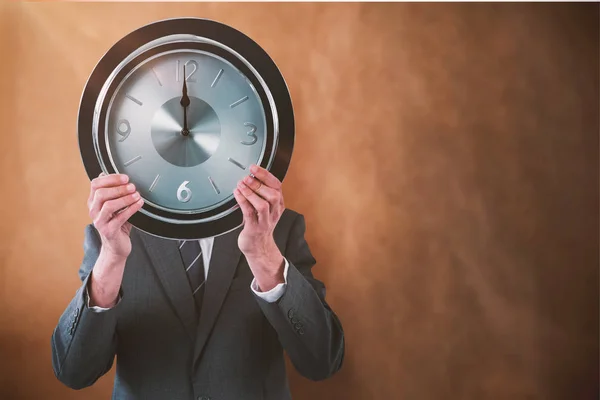 Hombre de negocios sosteniendo el reloj delante de su cara — Foto de Stock