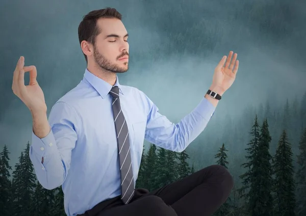 Business man meditating against foggy trees — Stock Photo, Image