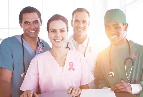 Medical team against cancer awareness ribbon — Stock Photo, Image