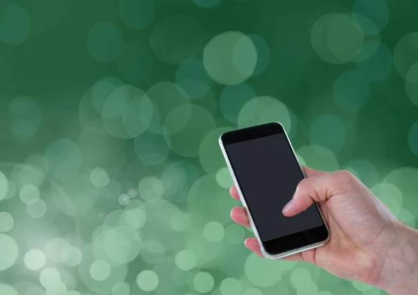 Mão segurando telefone com brilho bokeh verde — Fotografia de Stock