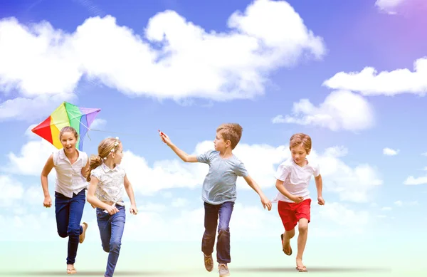 Boy holding kite running with friends — Stock Photo, Image