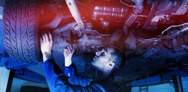 Mechanic under car in garage — Stock Photo, Image