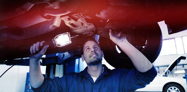 Mechanic shining torch under car — Stock Photo, Image