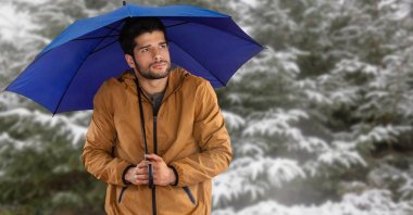 Adam kar ormandaki mavi şemsiye ile