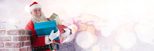 Santa sosteniendo regalos por chimenea — Foto de Stock