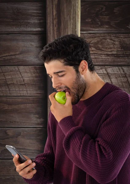 Mann mit Apfel und Handy gegen Holz — Stockfoto