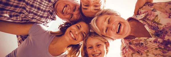 Glad familj bildar huddle mot himlen — Stockfoto
