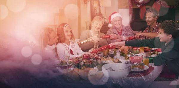 Οικογένεια, τραβώντας τις κροτίδες Χριστουγέννων στο τραπέζι του δείπνου — Φωτογραφία Αρχείου