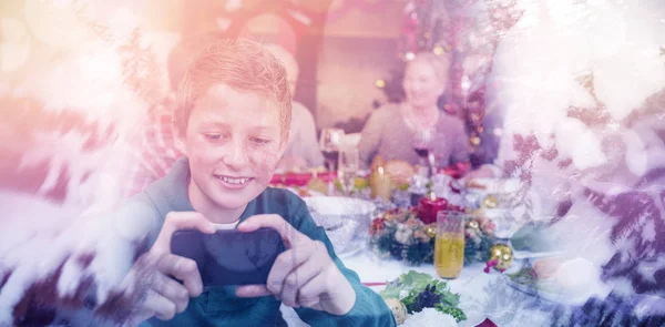 Niño sosteniendo teléfono inteligente durante la cena de Navidad —  Fotos de Stock