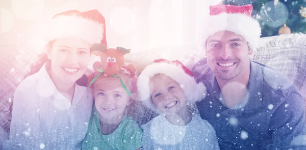 Family with Christmas hats sitting on the sofa — Stock Photo, Image